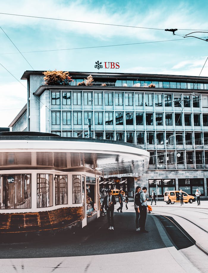Street scene in Zürich showcasing tramways, buildings, and people under a blue sky.