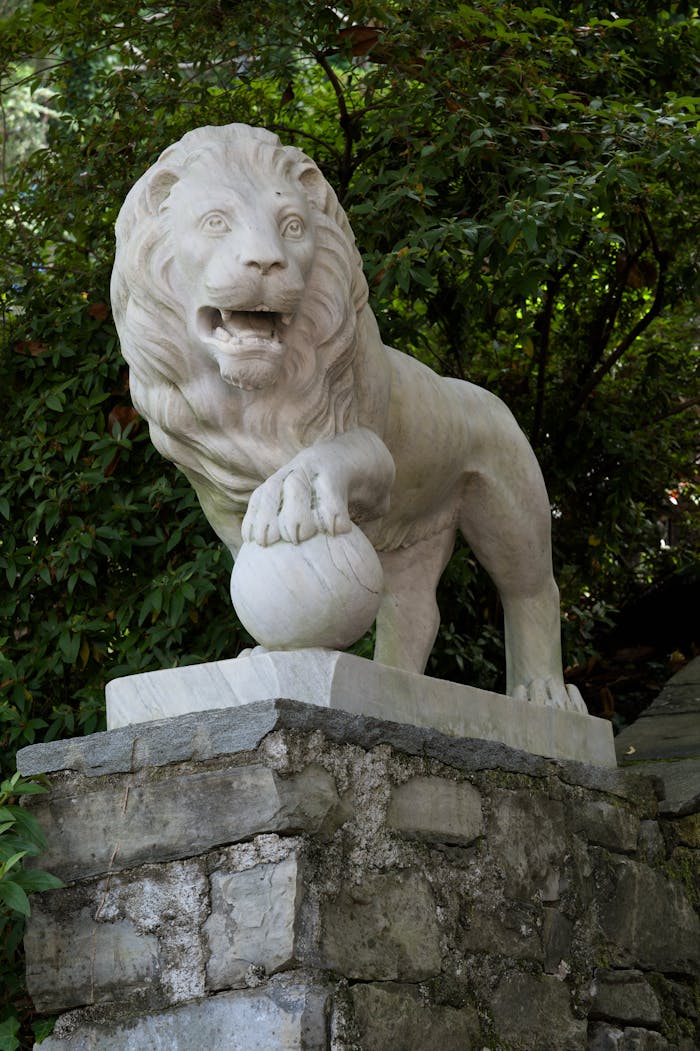 about-bg White marble lion statue in a lush garden setting in Morcote, Switzerland.