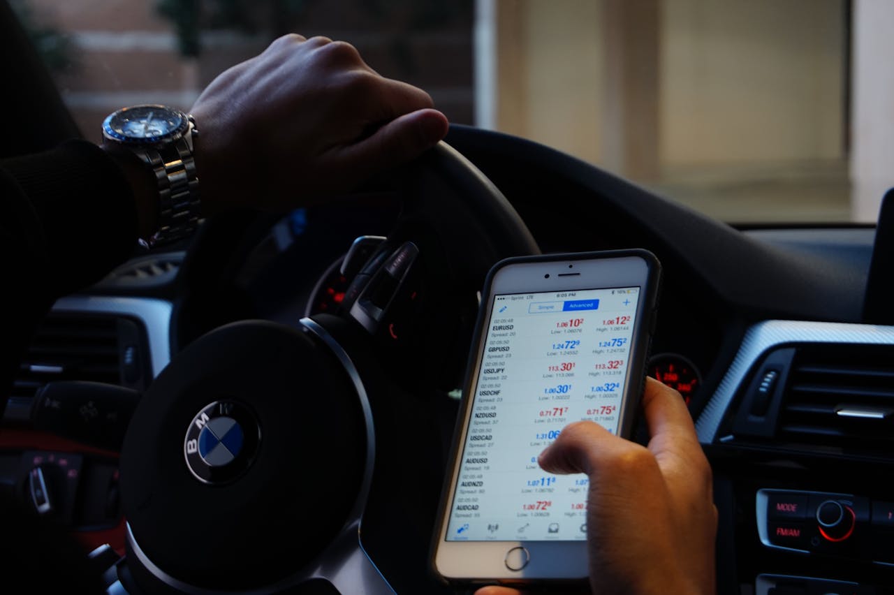 home-hero Person using mobile phone for currency trading while driving BMW car.